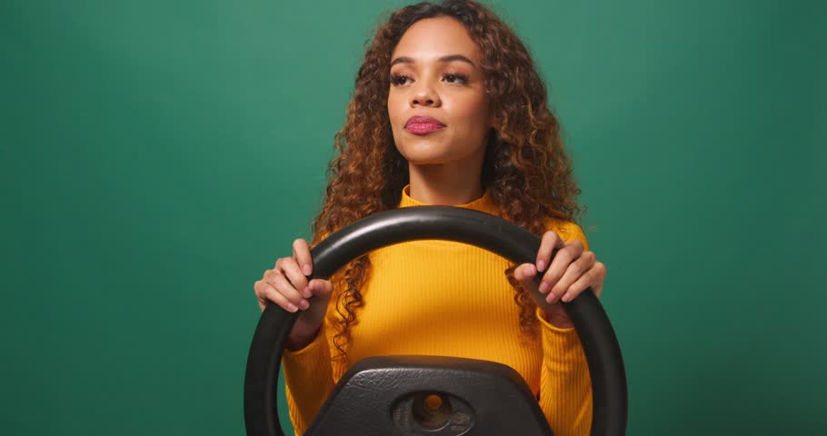 Young woman driver swerves and brakes to avoid accident, green studio background