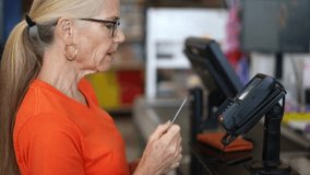 Slow motion closeup view of happy pretty mature woman using credit card to pay for groceries at grocery store checkout counter. - Powered by Shutterstock - Get 15% off with code: PIKWIZARD15