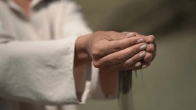 sand hands. close-up of the hand. woman in a linen suit. slow motion video. High quality Full HD video recording