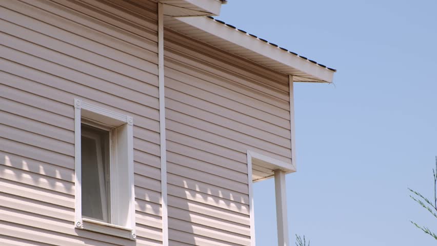 The facade of the new house clad with siding, with windows, against the blue sky. Royalty-Free Stock Footage #1106621859