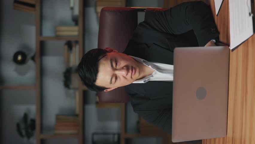 Vertical video of upset asian entrepreneur forming x with hands after shutting down laptop in office. Displeased business person stopping internal misuse of company's resources by employees. Royalty-Free Stock Footage #1106622309
