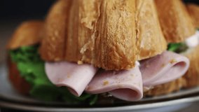 Croissant with ham, cheese, lettuce, slow rotation. Video 4 k resolution, close-up. Breakfast. Tasty sandwich. Puff pastry, do-it-yourself, delicious breakfast, calories