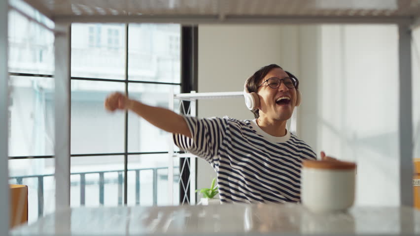 greeting happiness joyful asian adult male wearing casual cloth and wirreless headphone dance music lover while unpack stuff relax from home moving house relocation ,he is happy to move in new house