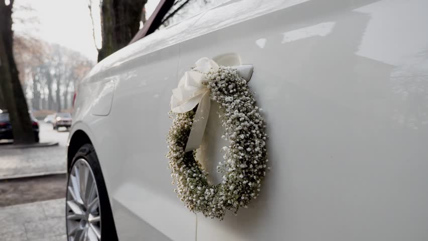 Beautiful wreath of flowers is attached to the car of the bride and groom. Wedding traditional decoration.