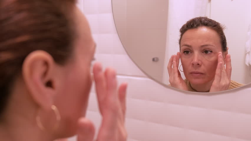 Woman looking at her wrinkles in front of a mirror Royalty-Free Stock Footage #1106628429
