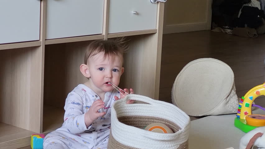 Toddler baby puts small objects in his mouth. The danger of small things getting into the child's mouth. Kid aged ten months