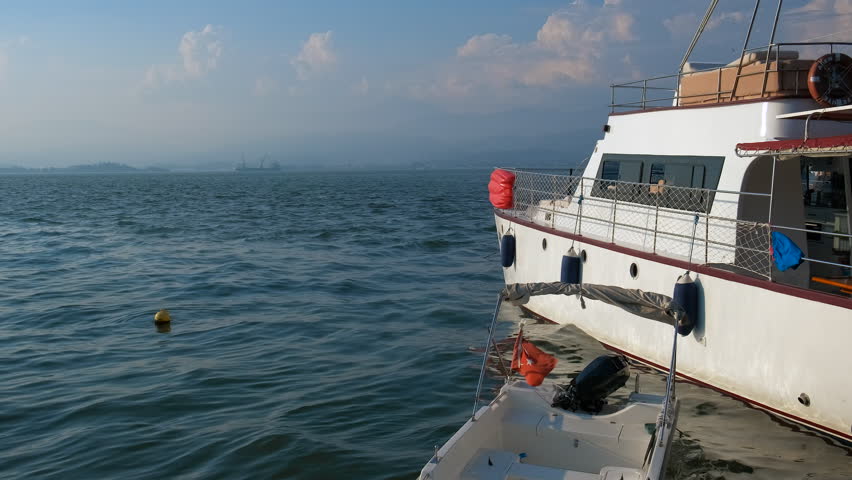 Wooden yacht moored against bay. A view of moored luxury wooden yacht against turquoise calm sea water at weekend.