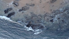 Big Waves rolling from above. Top down 4k drone view on blue turquoise ocean. Drone view of beautiful seamless never ending footage. Sea waves breaking on sandy coastline. Aerial vertical video. 