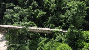 Rusted dilapidated metal bridge in tropical jungle Colombia camera panmomg along bridge Aerial video
