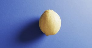 Vertical video of lemon with copy space on blue background. Fresh food, fruit and colour concept.