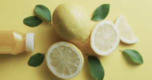 Vertical video of sliced lemon and juice with copy space over yellow background. Fresh food, fruit and colour concept.