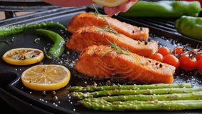 grilling fillet salmon with asparagus, tomato, lemon. A chef's hand is squeezing a fresh lemon over a peace of red sea fish. Cooking process. Slow motion. close up - Powered by Shutterstock - Get 15% off with code: PIKWIZARD15
