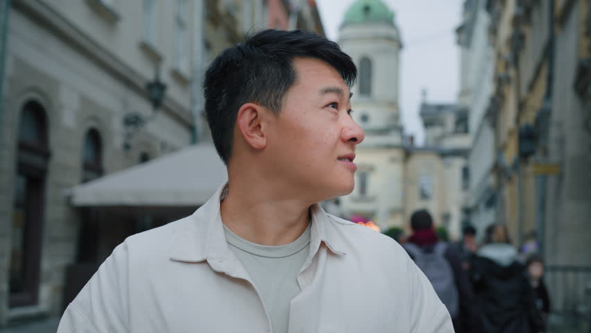 Male portrait happy smiling pensive inspired asian man tourist looking around outdoors dreaming chinese guy enjoying cityscape sightseeing standing in center city dream thinking examine architecture Royalty-Free Stock Footage #1106640535