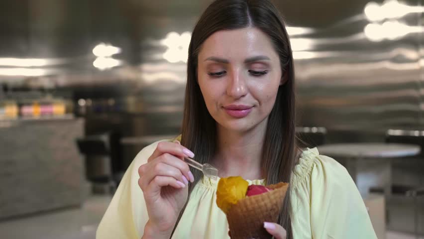 Beautiful young woman eating tasty ice cream in cafe