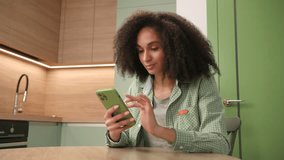 Woman Texting Using Smartphone. Black woman browsing online holding cell. Smiling young adult using mobile phone at home. - Powered by Shutterstock - Get 15% off with code: PIKWIZARD15