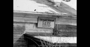 Village, house with inscription state bank. People with children walking along road. Winter, cold, snow, trees. Russia - december 1970s