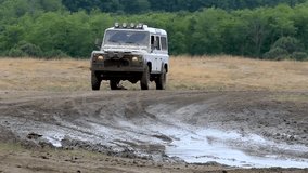 off-road vehicle splashes mud through a mud-filled pit