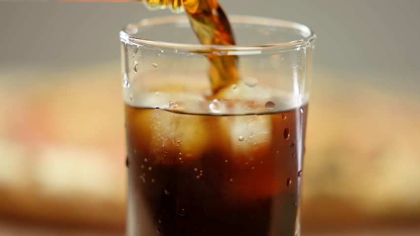 Close-up, hot fresh pepperoni pizza and a glass of cola with ice cubes. Carbonated sweet drink.