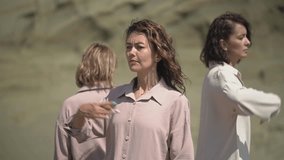 three Caucasian women in casual clothes are dancing. three women in the desert practice qigong. slow motion video. High quality Full HD video recording