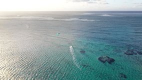4K footage sunset time from drone flying over tranquose coral reef bay with kiteboarder riding kiteboard. Active sport people and beauty in Nature concept aerial video. Le Morne beach, Mauritius.