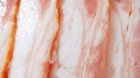 Juicy bacon slices dance in mesmerizing macro footage, revealing their mouthwatering texture and golden hues. A culinary masterpiece in motion. Processed food concept. Bacon background
