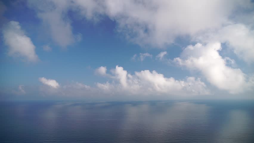 Timelapse of fluffy clouds moving in blue sky over calm sea. Abstract aerial nature summer ocean sunset sea and sky background. Vacation, travel and holiday concept Royalty-Free Stock Footage #1106657839