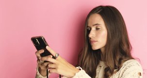 Attractive brunette woman make photo content for someone social media isolated on pink background. Woman make many photo on her mobile phone, turn her head and show thumb up.
