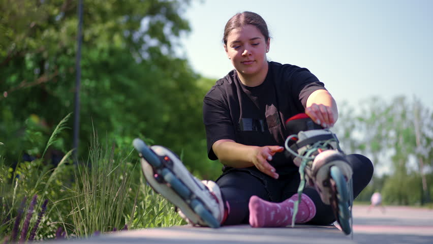 young hipster girl wearing roller skates tying laces skate park before skating street extreme sport