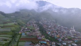 Aerial view of countryside on the mountain slope. FLy over Nepal Van Java, Mount Sumbing, Indonesia. Arrangement of terraced houses on a mountainside