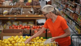 Slow motion view of smiling happy pretty mature woman selecting lemons in a grocery store. - Powered by Shutterstock - Get 15% off with code: PIKWIZARD15