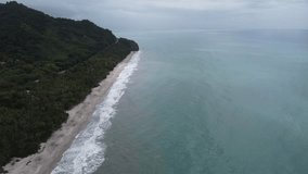 Looking down a beach in Northen Colombia Carribean sea with palm trees and blue water Aerial Video