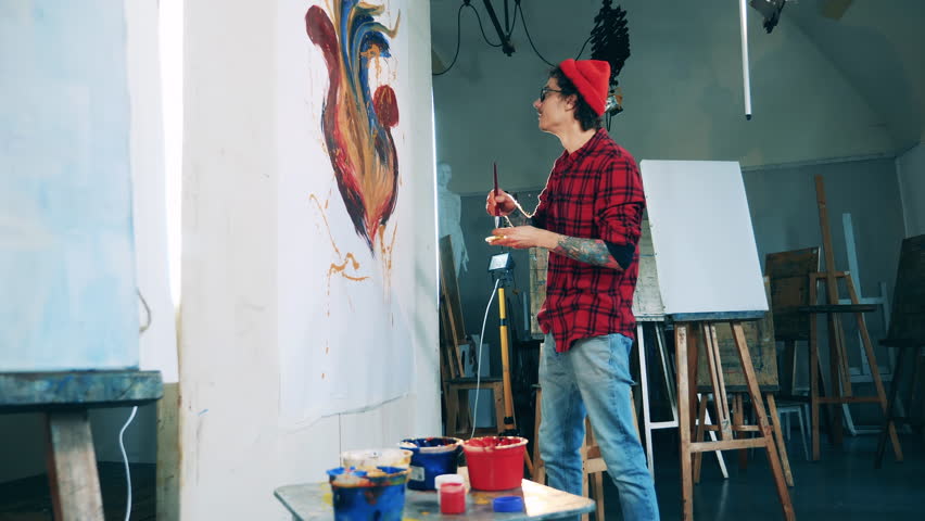 Male artist is working on his painting on a massive canvas Royalty-Free Stock Footage #1106664599