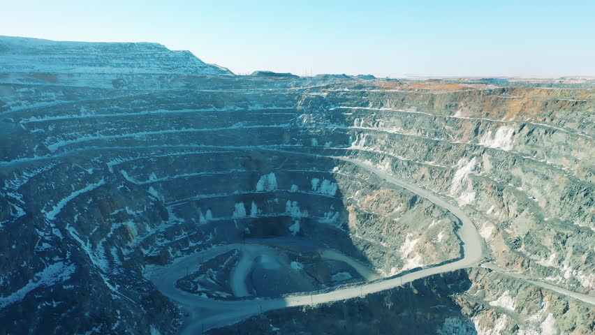 Copper mine deposit filmed as a landscape. Industrial quarry, heavy industrial machinery working at the mining open pit.