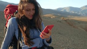 Young Woman using mobile phone in the autumn mountain. Female using trail map in the mountain. Profile of a happy mountaineer checking smart phone in the mountain. Happy Girl using cell phone sitting - Powered by Shutterstock - Get 15% off with code: PIKWIZARD15