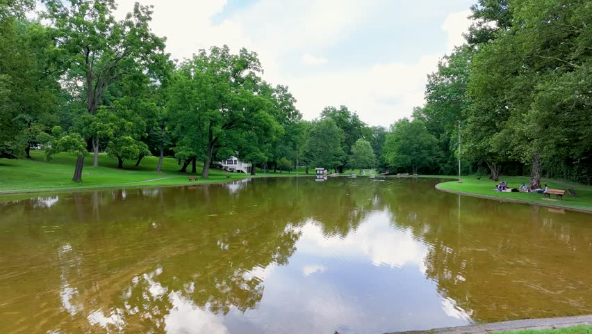 Drone footage of a small pond with walking trails leading to small creek