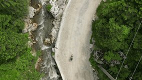 Drone following fit female cyclist is riding on gravel road in romanian mountains. Sport cycling motivation drone video. Woman cyclist riding between the mountains. Gravel adventure. 