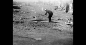 Worker digs hole in yard, construction, houses. Daytime, wide shot, spring. Russia 1970s.