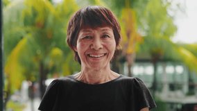 Portrait of Old Asian Woman Looking at Camera on Green Nature Background. Smiling Face and Beautiful Eyes of Happy Person Outdoors. Optimism of Successful Adult Female Standing on City Street of Asia - Powered by Shutterstock - Get 15% off with code: PIKWIZARD15