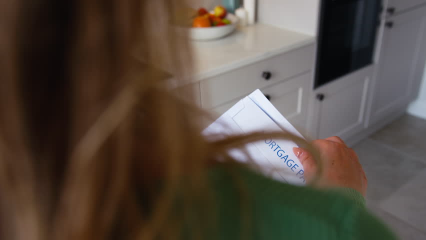 Close up of woman at home opening and reading letter about increase in mortgage rate repayment during cost of living crisis - shot in slow motion Royalty-Free Stock Footage #1106696907