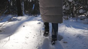Unrecognizable woman in winter clothes walking through snowy forest stepping on deep snow. Back view on legs of female hiker having stroll at cold winter day. Girl going outdoor. POV Slow mo Close up - Powered by Shutterstock - Get 15% off with code: PIKWIZARD15