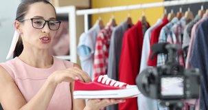 Young woman blogger with glasses showing sports shoes in front of camera 4k movie