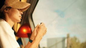 Beautiful woman applies her lipstick in front of the window while traveling by train