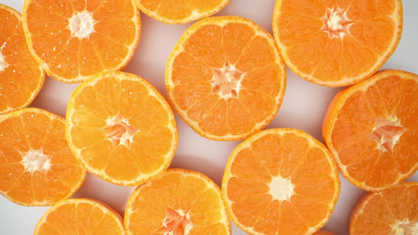 Macro video, a group of oranges slices is revealed, each one delicately cut in half. The vibrant colors and intricate textures come to life, capturing the juicy essence of these citrus delights. 4K
