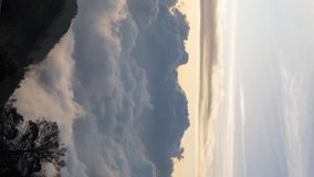 Vertical video - Timelapse of the sun setting over layers of rolling clouds on the mountain, taken in Mount Bromo, Indonesia