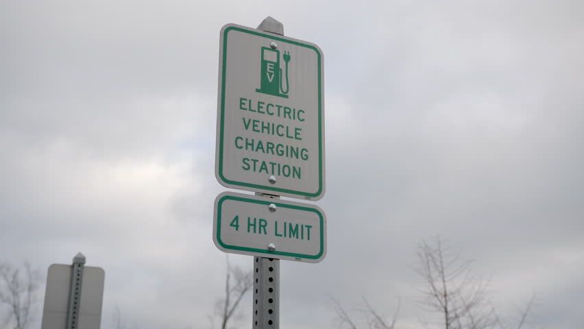 Electric Vehicle EV Charging Station parking spot on cloudy stormy day. This wouldn't have been good for solar vehicles, but EV charging station is made to quickly replenish low batteries. Royalty-Free Stock Footage #1106709633