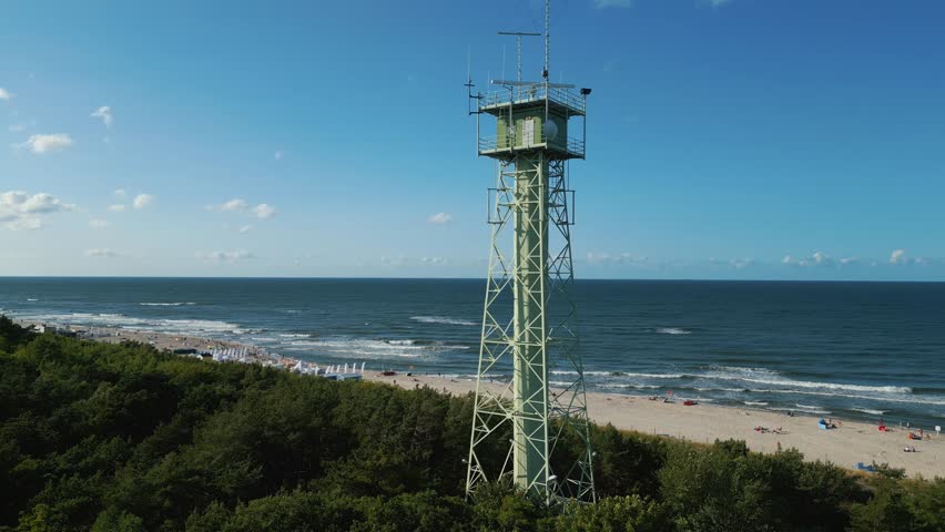 border observation tower with radar and antenna, sea shore with beach, 4k aerial