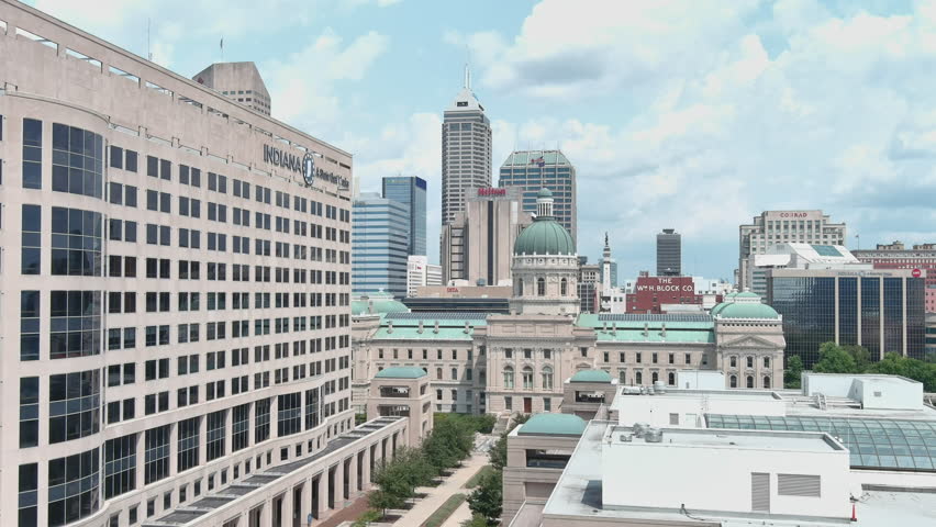 Flying by Indiana statehouse and government building with Indianapolis skyline. A State That Works motto on side of building.