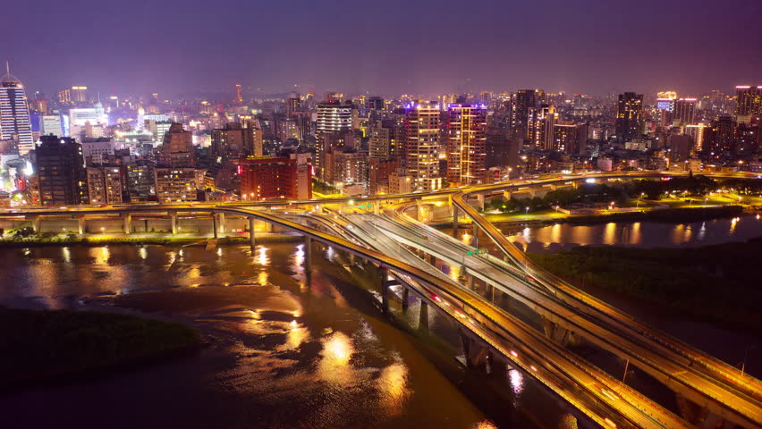 Night view of busy traffic on Zhongxing Bridge over Tamsui River and the riverside Huanhe Expressway in vibrant Taipei City, with a crowded buildings in Ximending Downtown and 101 Tower in background