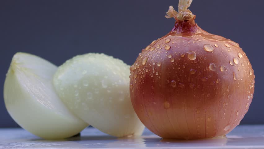 Water is poured on chopped onion from above on an red background, white delicious onion in water with close-up. Filmed on cinema camera, 8K downscale, 4K.