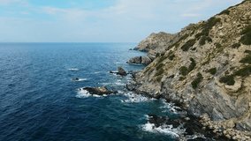 Rocky coastline with rocky reefs and crashing sea waves of Aegean sea, Aerial dolly shot